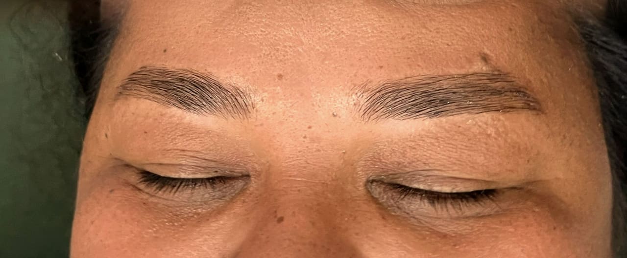 Cliente deitada na maca, de olhos fechados, com as sobrancelhas recém-desenhadas